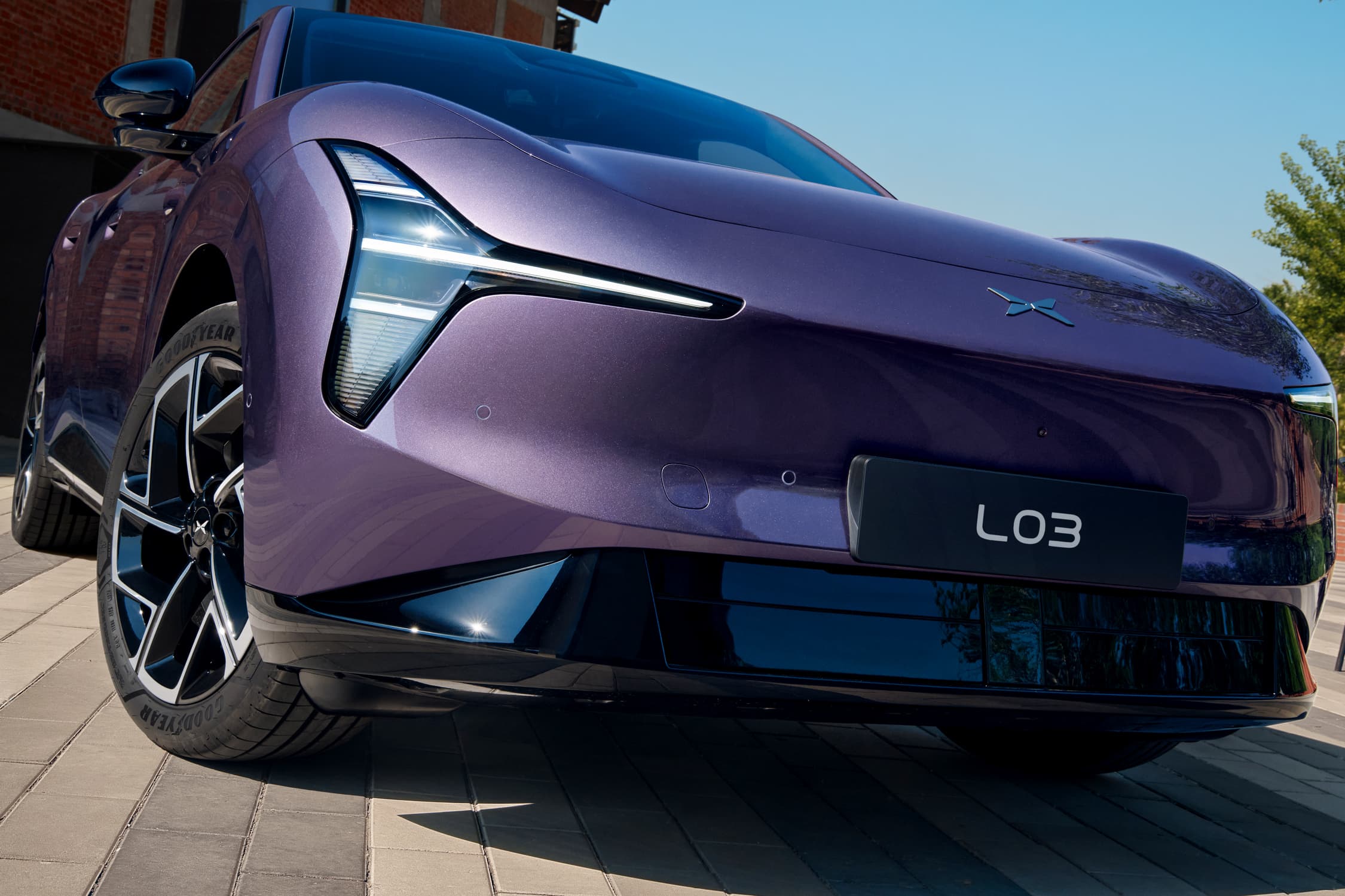 Xpeng L03 low-angle front three-quarter view on a sunny street, purple colorway